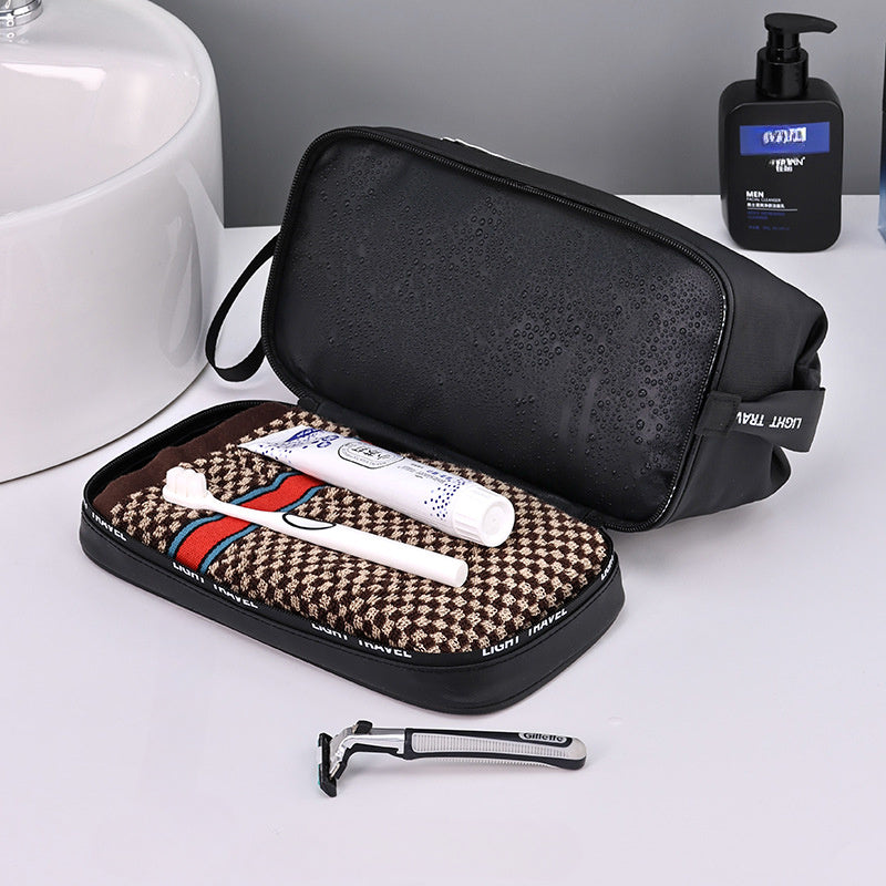 Nécessaire da viaggio nero con spazzolino, dentifricio e rasoio su asciugamano marrone. Accessori bagno eleganti e pratici per uomo.