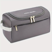 Borsa da viaggio grigia con cerniera, manico laterale e tasca frontale, ideale per organizzare accessori da viaggio. Design compatto e resistente.