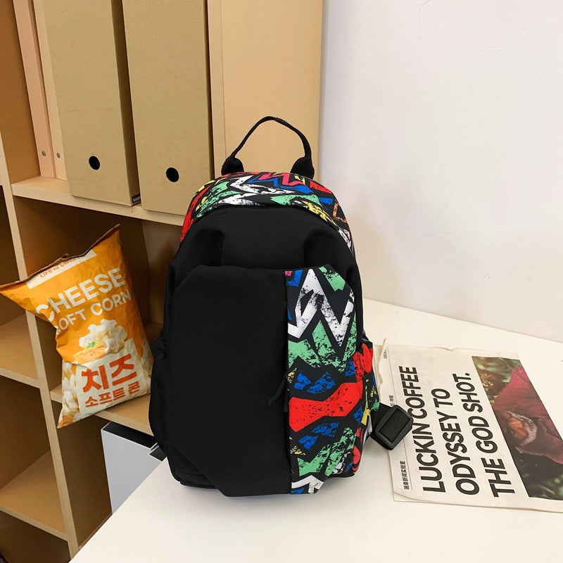 Zaino colorato con motivo astratto su scrivania, accanto a busta di popcorn al formaggio e rivista. Accessorio moda, scuola, viaggio.
