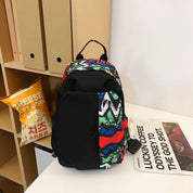 Zaino colorato con motivo astratto su scrivania, accanto a busta di popcorn al formaggio e rivista. Accessorio moda, scuola, viaggio.