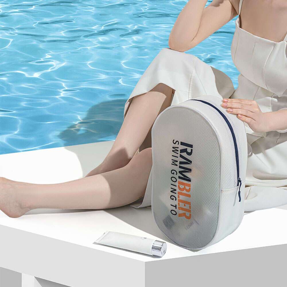 Donna seduta vicino a piscina con borsa bianca RM Beer e crema solare. Moda estiva, accessori piscina, relax al sole.