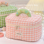 Borsa cosmetica a quadretti rosa con manico imbottito, cerniera e etichetta "the jolly house". Design elegante per organizzare trucchi e accessori.