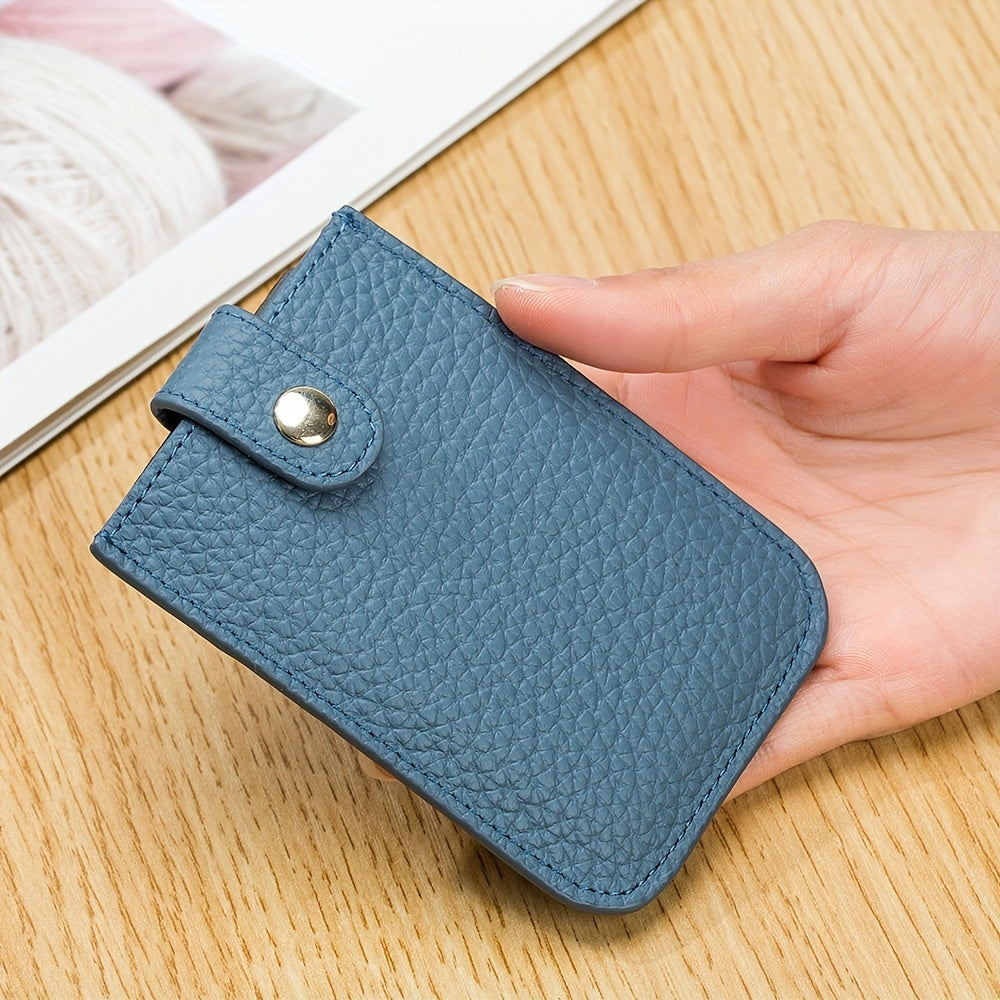 Portafoglio in pelle blu compatto, tenuto in mano su tavolo di legno. Design elegante, chiusura a bottone, ideale per carte e contanti. Accessorio moda.
