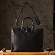 Borsa a mano in pelle nera con tracolla regolabile, cuciture bianche a contrasto, su sfondo rustico. Elegante accessorio moda donna.