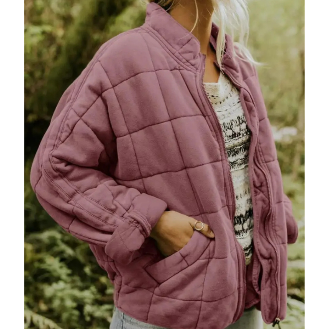 Giacca trapuntata viola da donna, stile casual, con tasche laterali. Perfetta per l'autunno, abbinata a maglia bianca e jeans. Moda femminile outdoor.