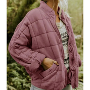 Giacca trapuntata viola da donna, stile casual, con tasche laterali. Perfetta per l'autunno, abbinata a maglia bianca e jeans. Moda femminile outdoor.
