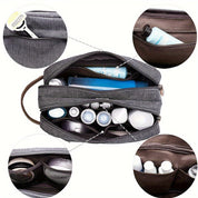 Borsa da toilette grigia con scomparti multipli, contenente articoli da viaggio come rasoi, flaconi e tubetti. Organizzatore da viaggio compatto.