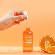 Bottiglia di siero alla vitamina C Dr. Rashel con contagocce, sfondo arancione, mezza arancia fresca. Skincare, antiossidante, anti-invecchiamento.