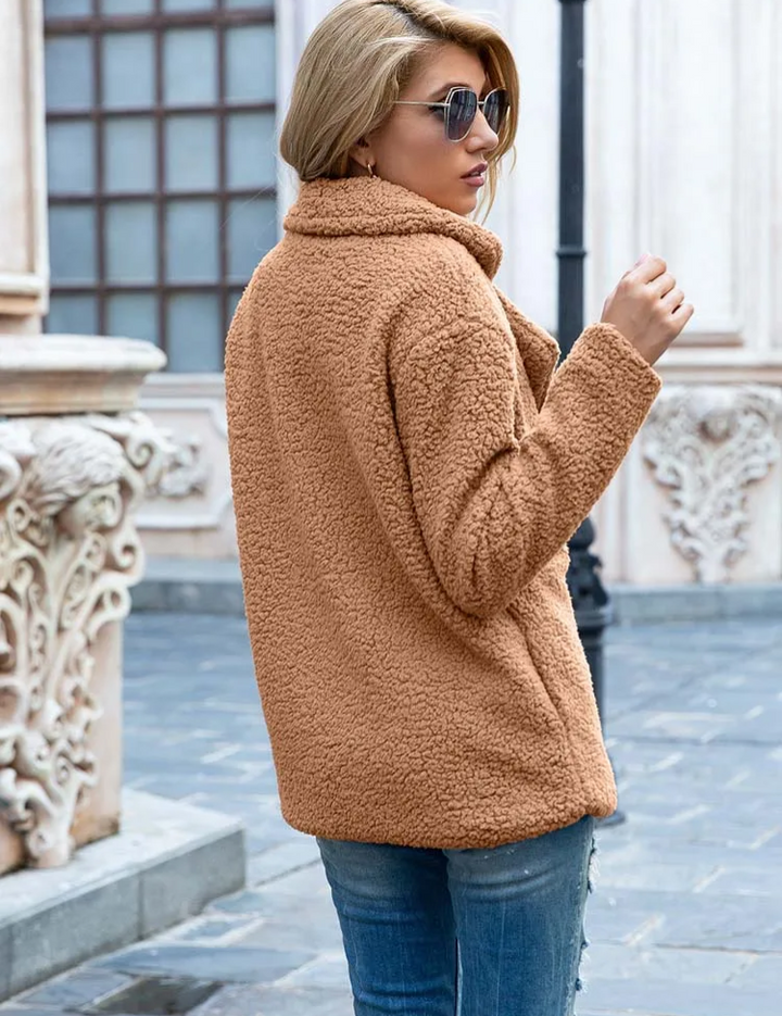 Donna con giacca in pelliccia sintetica marrone, jeans, occhiali da sole, in strada urbana. Moda autunnale, abbigliamento casual elegante.