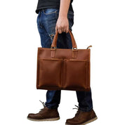 Uomo con borsa a mano in pelle marrone, tasche frontali, jeans e stivali. Accessorio moda maschile, elegante e pratico per lavoro o viaggio.