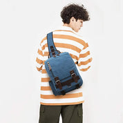 Giovane con zaino blu in tela, stile casual, indossa maglia a righe arancioni e bianche. Moda urbana, accessori uomo, tendenze 2023.