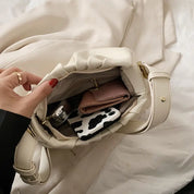 Borsa a tracolla bianca aperta con portafoglio rosa, custodia maculata e accessori. Design elegante, moda donna, accessori di tendenza.