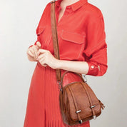 Donna con abito rosso indossa borsa a tracolla in pelle marrone, design elegante e moderno, accessorio moda femminile, perfetto per ogni occasione.