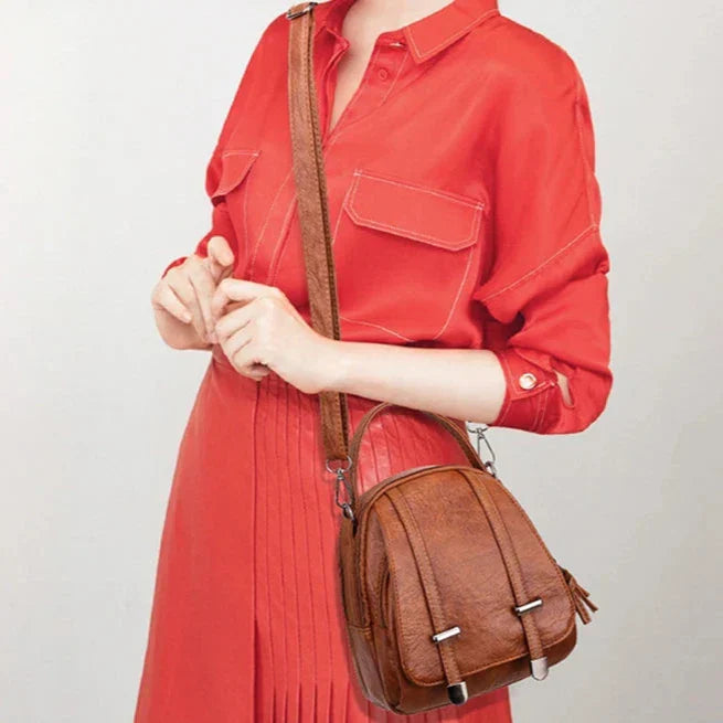 Donna con abito rosso indossa borsa a tracolla in pelle marrone, design elegante e moderno, accessorio moda femminile, perfetto per ogni occasione.
