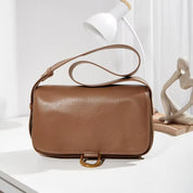 Borsa a tracolla in pelle marrone su tavolo bianco, design elegante e minimalista, perfetta per moda donna, accessorio di tendenza.