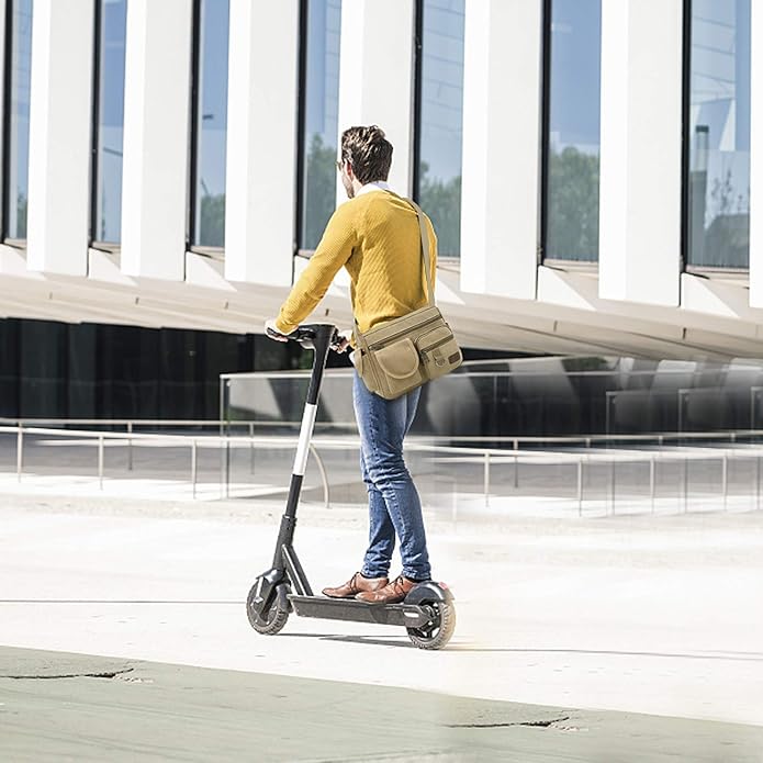 Uomo su monopattino elettrico nero, indossa maglione giallo e jeans, davanti a edificio moderno. Mobilità urbana sostenibile.