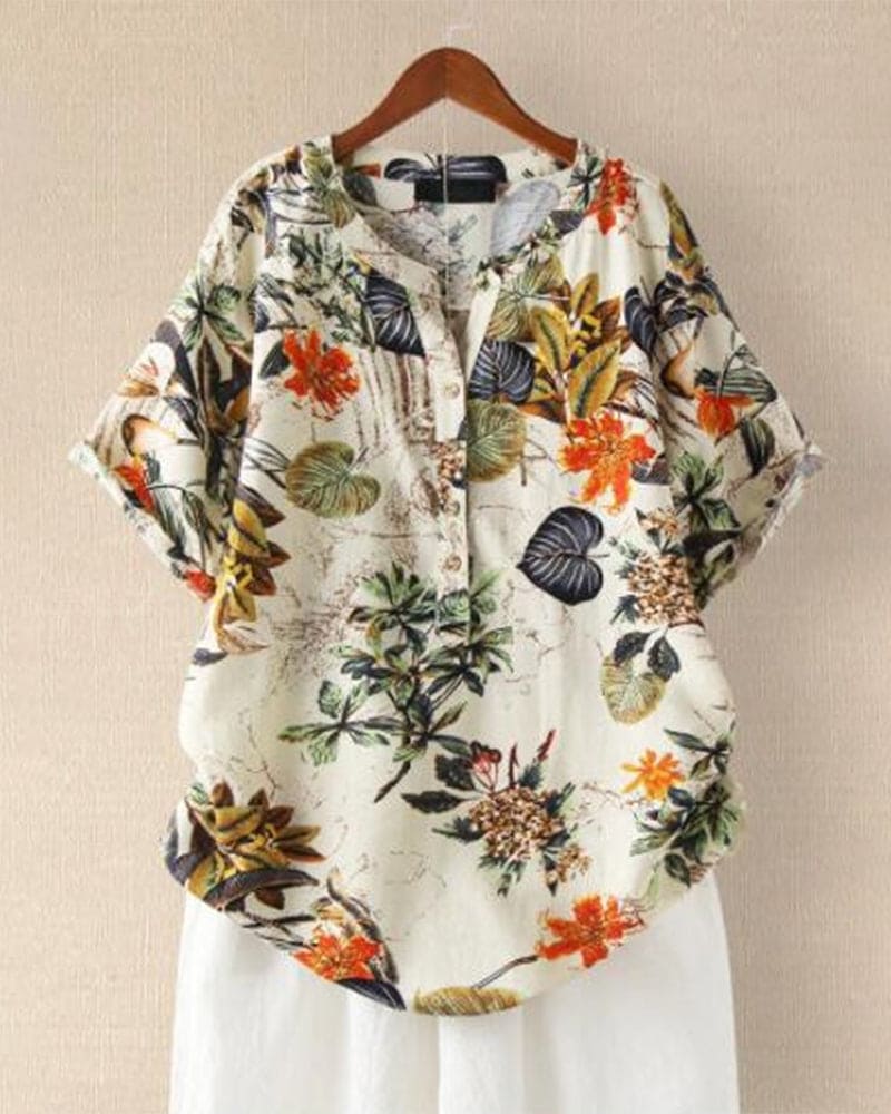 Camicia donna floreale, maniche corte, bottoni, stampa tropicale, colori vivaci, casual, estiva, su gruccia, sfondo beige.