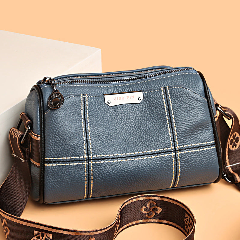 Borsa a tracolla in pelle blu con cuciture bianche, cerniera superiore e tracolla regolabile marrone. Design elegante e moderno per donna.