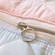 Cerniera in metallo su copripiumino trapuntato rosa e bianco, dettaglio tessuto morbido, chiusura resistente, accessorio camera da letto elegante.