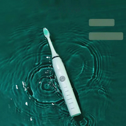 Spazzolino elettrico bianco impermeabile su superficie d'acqua verde, design moderno, setole morbide, ideale per igiene orale avanzata.