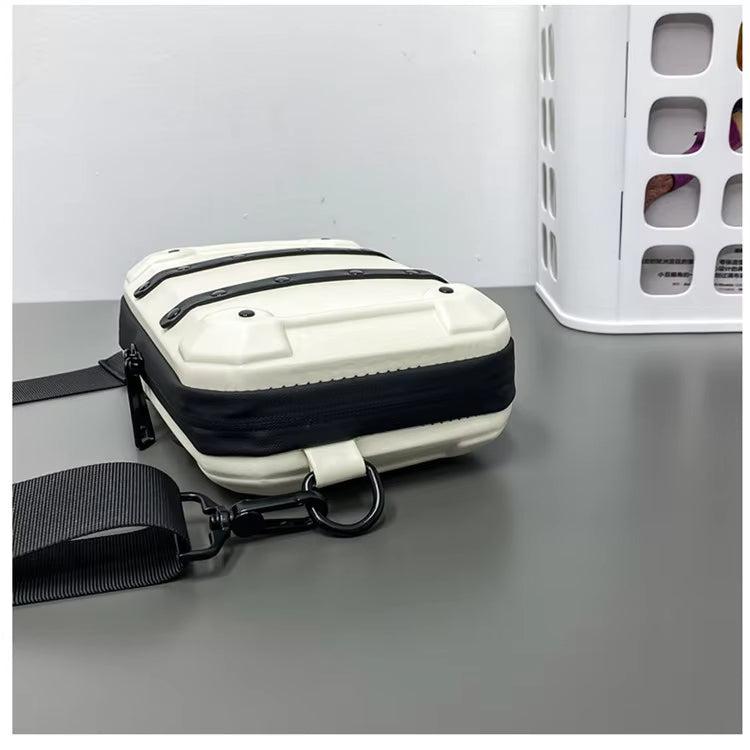 Borsa a tracolla bianca e nera su tavolo grigio, design moderno e compatto, ideale per uomo e donna, accessorio moda unisex.