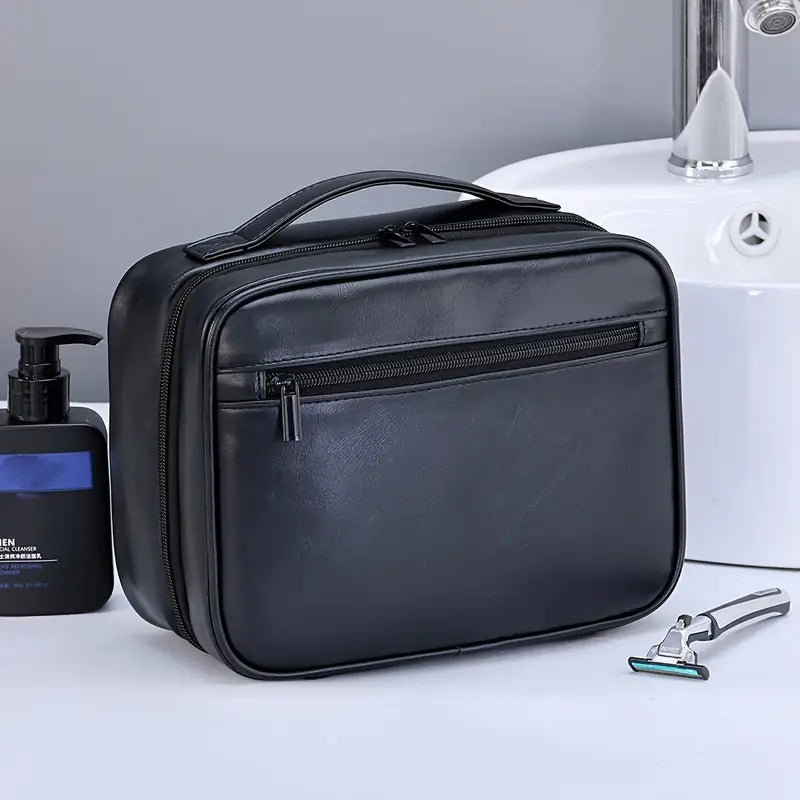 Elegante borsa da toilette in pelle nera con cerniera, ideale per viaggi. Accessori bagno inclusi: rasoio e dispenser sapone. Perfetta per organizzare.
