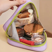 Astuccio cosmetico viola aperto con trucchi vari, tra cui rossetto rosso, cipria compatta e flaconi. Organizzatore da viaggio per make-up.