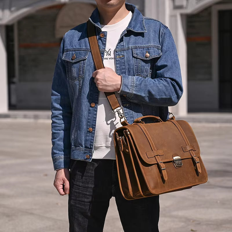 Uomo con giacca di jeans indossa borsa a tracolla in pelle marrone, stile vintage, all'aperto. Accessorio moda maschile, casual ed elegante.