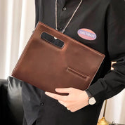 Uomo con camicia nera tiene una borsa a mano in pelle marrone, elegante e moderna, ideale per lavoro o ufficio. Accessorio moda maschile.