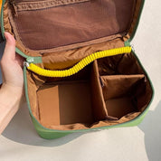 Zaino verde aperto con scomparti interni regolabili e tasca a rete marrone, ideale per organizzazione e trasporto. Accessorio versatile e pratico.