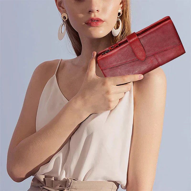 Donna con portafoglio rosso in pelle, elegante e moderno, indossa orecchini pendenti e top bianco. Accessorio moda femminile di tendenza.