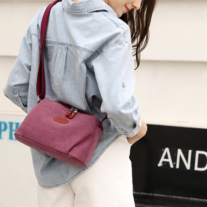 Donna con camicia di jeans e borsa a tracolla rosa in tessuto, stile casual. Accessorio moda femminile, ideale per look quotidiani e shopping.