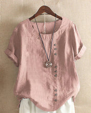 Blusa donna in lino rosa con bottoni decorativi, maniche corte risvolte, scollo rotondo, abbinata a collana pendente. Stile casual elegante.