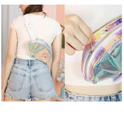 Donna con marsupio olografico iridescente, indossato a tracolla su maglietta bianca e shorts di jeans. Accessorio moda trendy e luminoso.