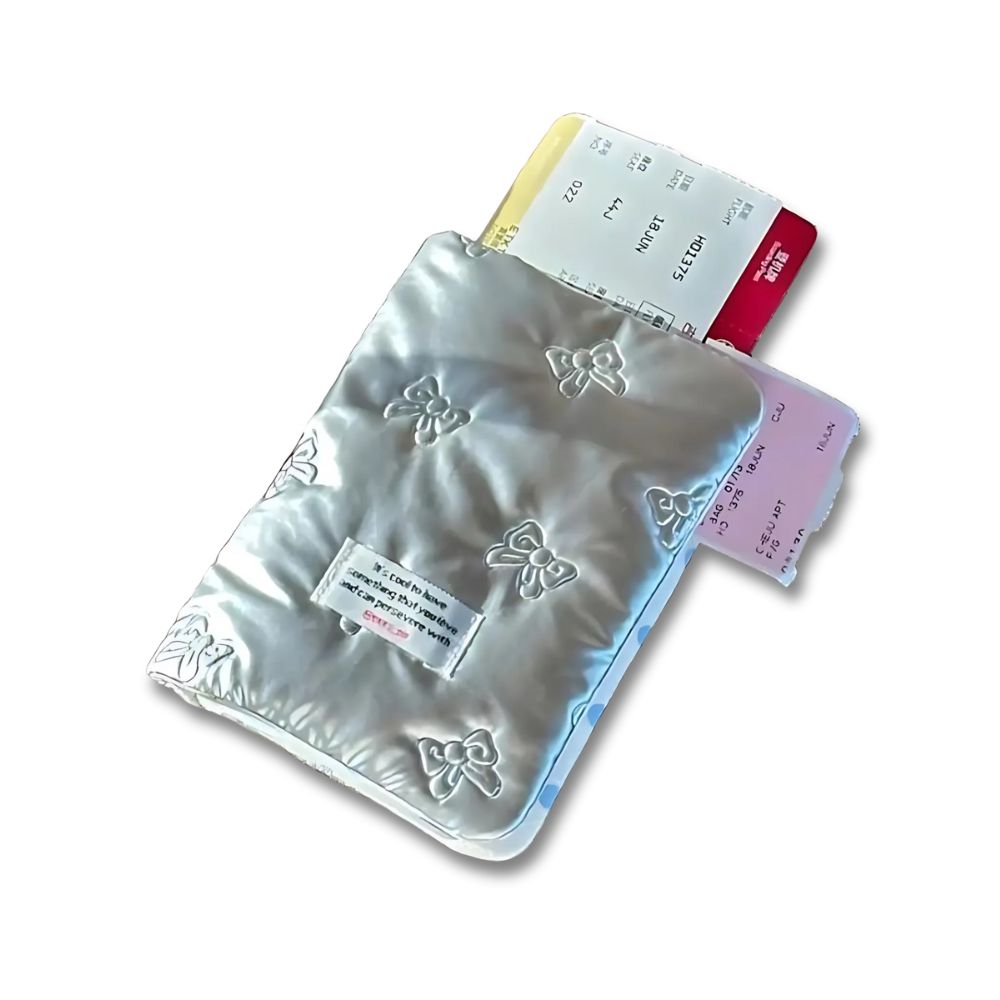 Porta passaporto argentato con motivo a fiocco, contenente biglietti aerei colorati. Accessorio da viaggio elegante e funzionale.