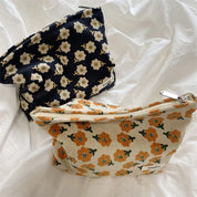 Due pochette in tessuto floreale, una blu con fiori bianchi e una beige con fiori arancioni, su sfondo bianco. Accessori moda eleganti e pratici.