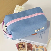 Borsa da toilette blu con cerniera rosa su libro "Book of Bread", design moderno, ideale per viaggi, accessori bagno, organizer cosmetici.