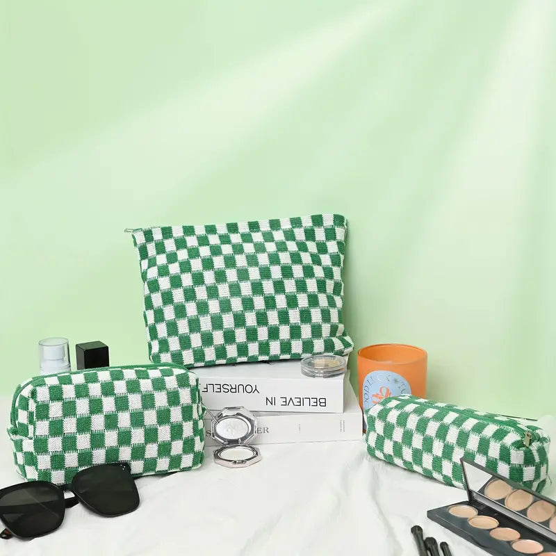 Set di borse da trucco a scacchi verdi e bianchi su sfondo verde, con occhiali da sole, cosmetici e libri. Accessori moda eleganti e pratici.