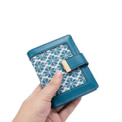 Portafoglio donna in pelle blu con motivo floreale, chiusura a scatto dorata. Design elegante e compatto, ideale per moda e accessori femminili.