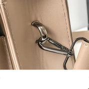 Gancio in metallo su borsa in pelle beige, dettaglio di design elegante. Accessorio moda donna, chiusura sicura, stile moderno.