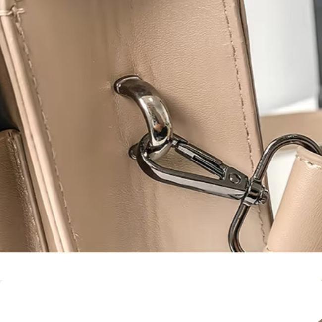 Gancio in metallo su borsa in pelle beige, dettaglio di design elegante. Accessorio moda donna, chiusura sicura, stile moderno.