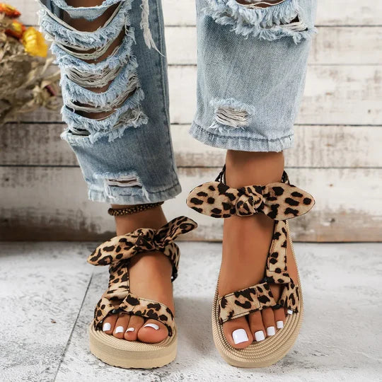 Sandali con zeppa leopardati, donna, suola in gomma, lacci annodati, abbinati a jeans strappati. Scarpe estive moda casual, stile trendy.