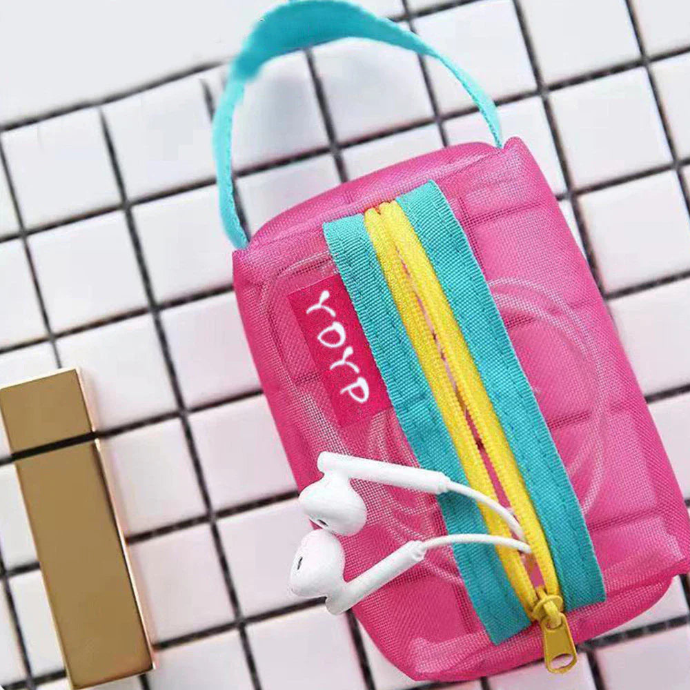 Custodia rosa trasparente con cerniera gialla e blu, contenente auricolari bianchi, su sfondo a piastrelle bianche. Accessorio moda pratico e colorato.