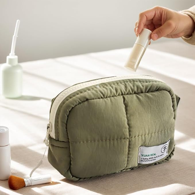 Borsa da toilette verde imbottita su tavolo, con flacone cosmetico e pennello. Accessori da viaggio, organizzazione, cura personale.