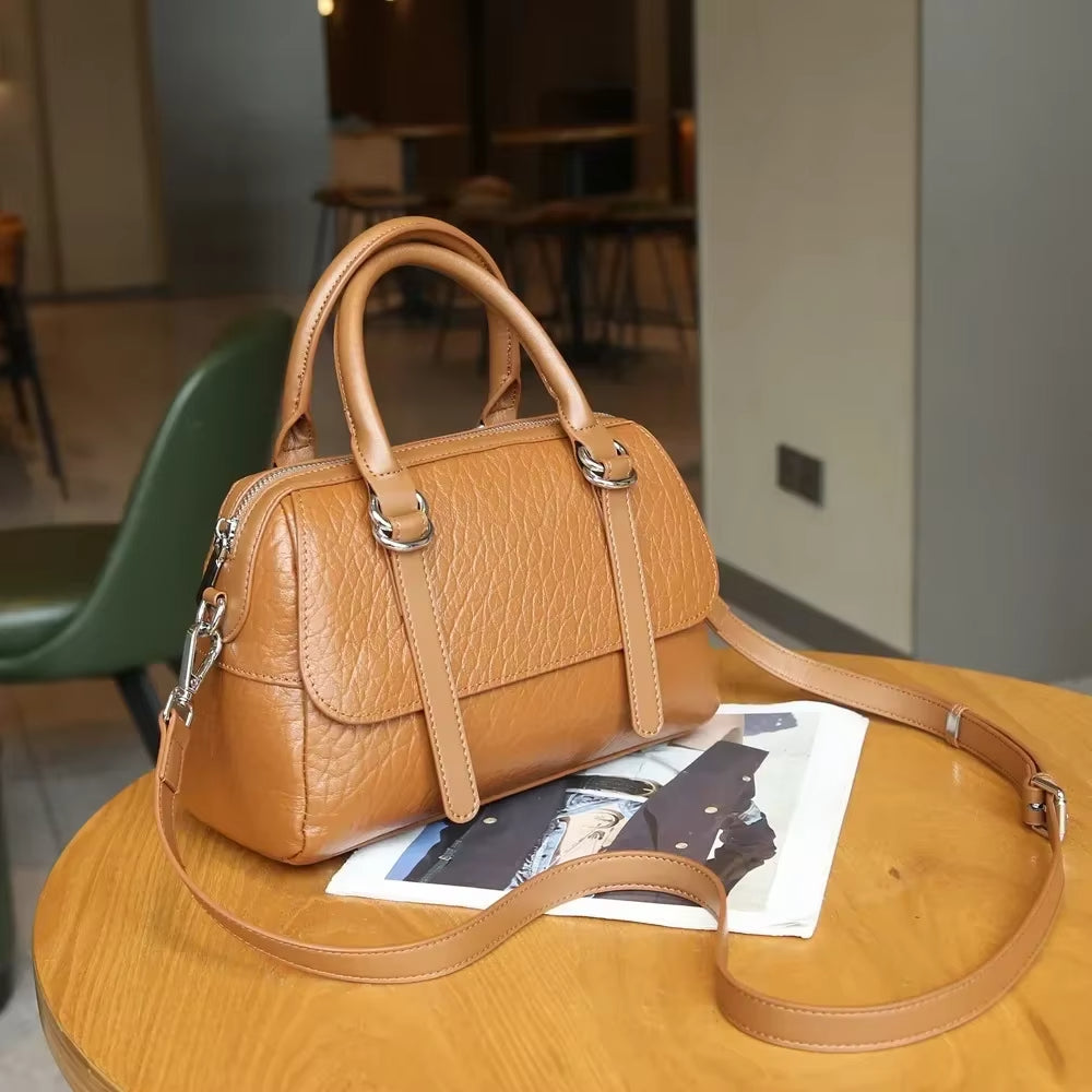 Borsa a mano in pelle marrone su tavolo di legno, design elegante con tracolla regolabile, perfetta per moda donna e accessori di lusso.