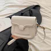 Borsa a tracolla bianca elegante su sfondo nero, design moderno con chiusura a patta, ideale per moda femminile e accessori di tendenza.