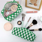 Set di borse trucco a scacchi verdi e bianche con pennelli cosmetici, cipria, profumo e specchio. Accessori beauty eleganti e funzionali.