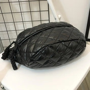 Zaino nero trapuntato su sedia bianca, design moderno e compatto, ideale per moda urbana. Accessorio versatile per uomo e donna.