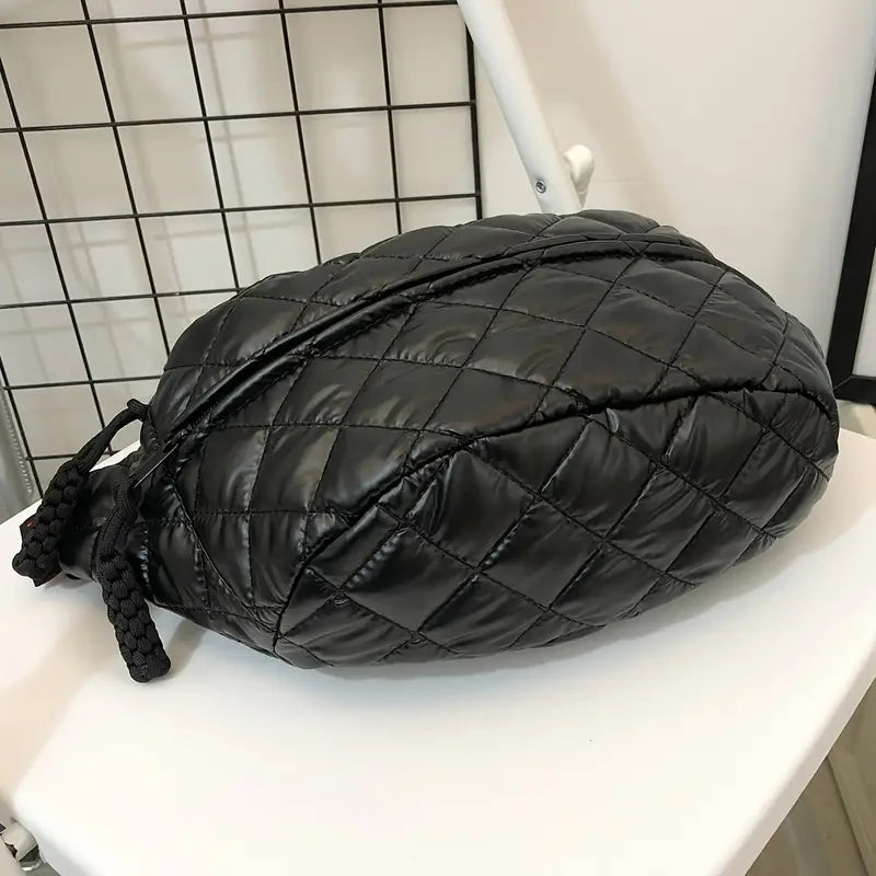 Zaino nero trapuntato su sedia bianca, design moderno e compatto, ideale per moda urbana. Accessorio versatile per uomo e donna.