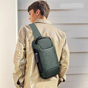 Zaino monospalla verde su uomo con giacca beige, design moderno e compatto, ideale per viaggi e uso quotidiano. Accessorio moda pratico e versatile.